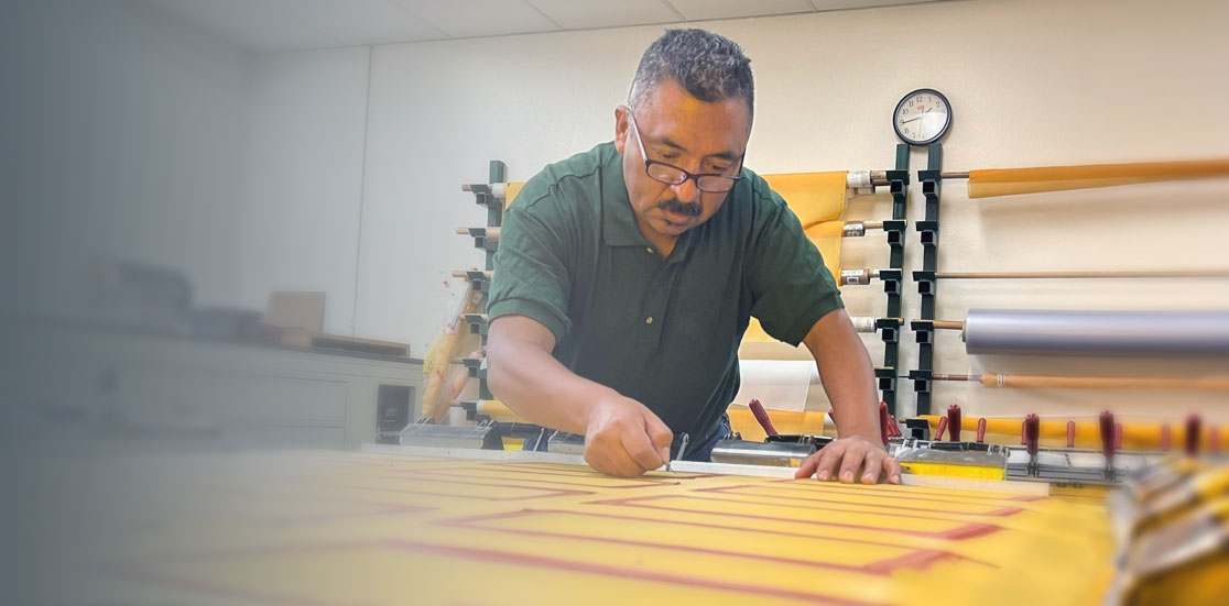Deco Tech technician tensioning mesh during custom screen making