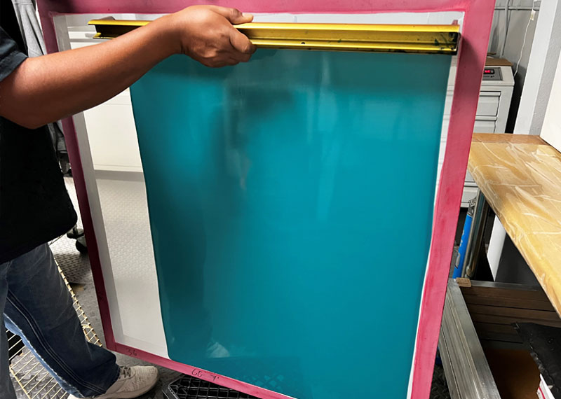 Photo emulsion being applied to an industrial screen printing screen