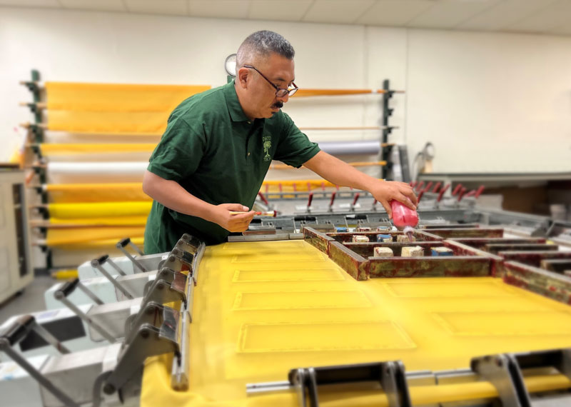 Deco Tech technician working on a stretch and glue screen printing frame